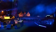 Jörg Achim Keller dirigiert die NDR Bigband auf nächtlicher Bühne, im Vordergrund Pianist Vladyslav Sendecki, an der Bühnenkante Solist Claus Stötter an der trompete, Konzertreise Danzig im August 2012 © NDR Foto: Philip Artus