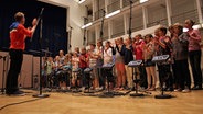 Ein Kinderchor nimmt in einem Studio ein Lied auf. © NDR 