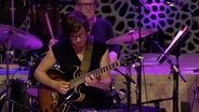 Sandra Hempel spielt Gitarre, im Hintergrund ihre Kollegen von der NDR Bigband. © NDR 