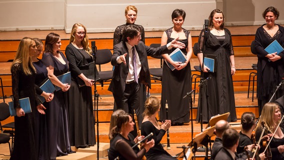 Konzertszene: Vaclac Luks bittet Sänger und Musiker, für den Applaus aufzustehen © NDR Foto: Axel Herzig