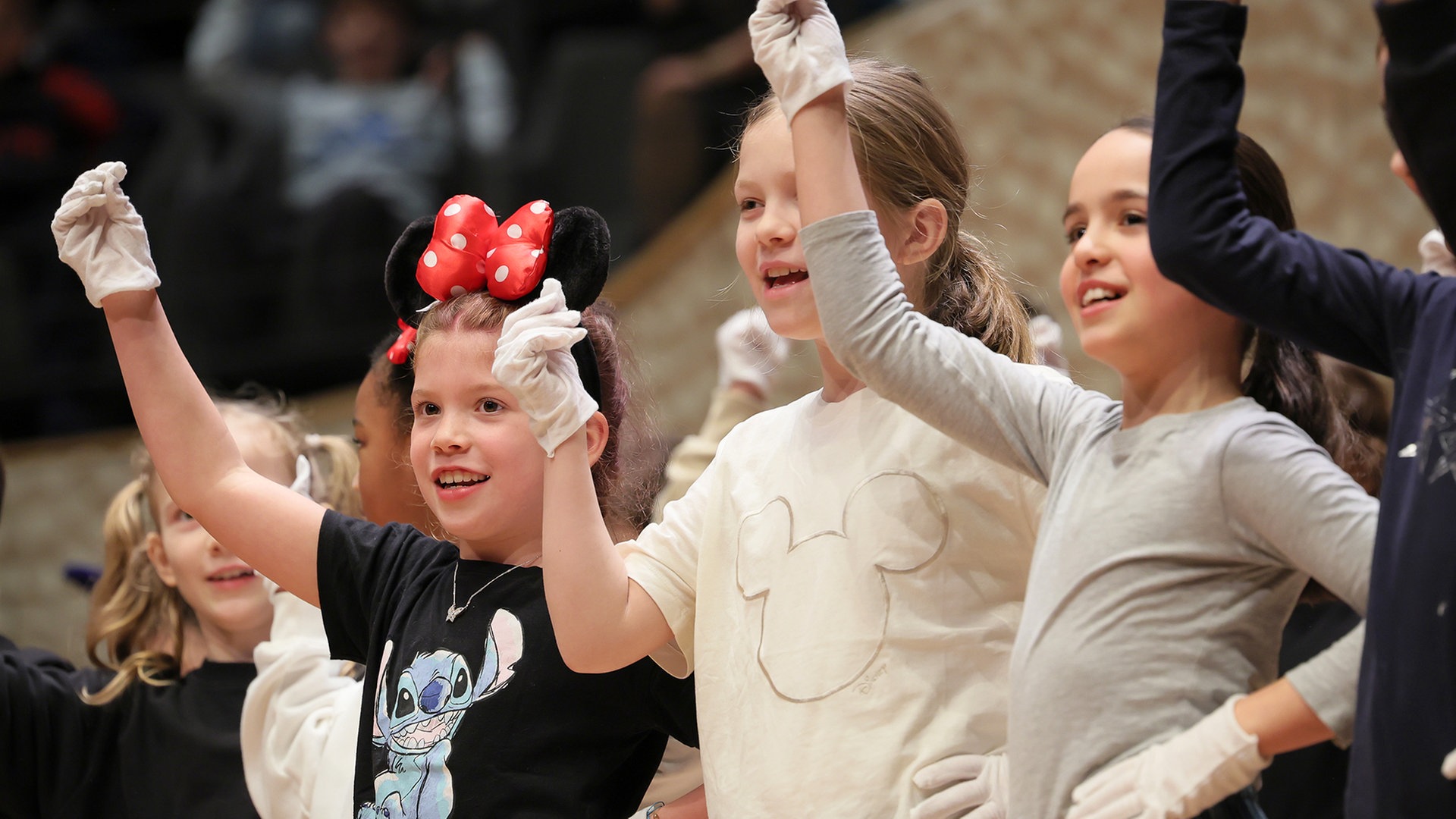 Konzertszene aus einem Discover-Music-Konzert: Verkleidete Kinder mit Handschuhen und Minnie-Maus-Ohren gestikulieren auf der Bühne © NDR Foto: Marcus Krüger
