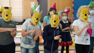 NDR Discover Music zu Besuch in Schulen: Grundschulkinder tanzen mit Partyhüten einer Winnie-der-Pu-Maske im Gesicht in einer Turnhalle © Sebastian Torres Foto: Sebastian Torres