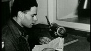 Ein Mann sitzt vor einem Mikrofon (1945). © NDR 