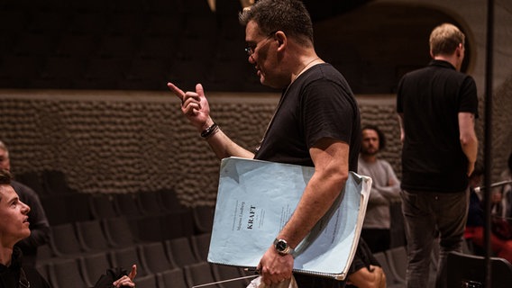 Probenszene: Alan Gilbert im Gespräch auf der Bühne der Elbphilharmonie Hamburg. Unter dem Arm trägt er eine Partitur von Magnus Lindbergs "Kraft". © NDR Foto: Peter Hundert