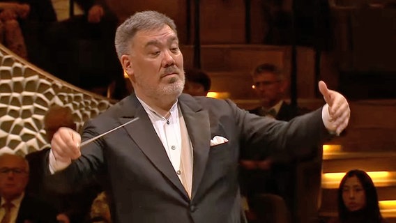 Screenshot: Chefdirigent Alan Gilbert dirigiert auf der Bühne der Elbphilharmonie beim Silvester-Konzert des NDR Elbphilharmonie Orchesters. © NDR EO Foto: Screenshot