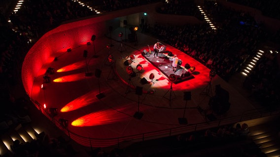 JOCO auf der rot beleuchteten Bühne der Elbphilharmonie. © Benjamin Hüllenkremer Foto: Benjamin Hüllenkremer