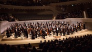 Konzertszene: Das NDR Elbphilharmonie Orchester mit Alan Gilbert beim Schlussapplaus auf der Bühne der Elbphilharmonie Hamburg © NDR Foto: Peter Hundert
