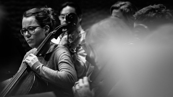 Probenszene: Cellistin Katharina Kühl und andere Musiker des NDR Elbphilharmonie Orchesters in einer Probe (Schwarz-weiß-Bild) © NDR Foto: Peter Hundert