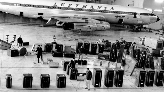 Orchesteraufstellung mit Koffern in der Flugzeughalle von New York (1963). © NDR 