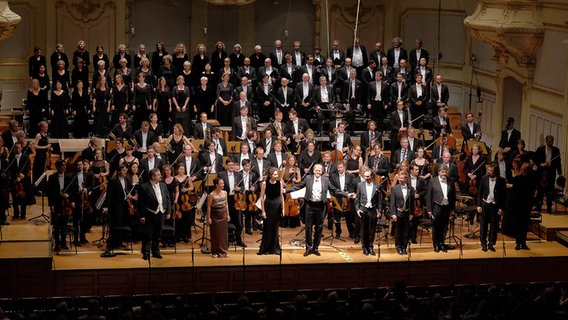 Konzertszene: Orchester, Chöre, Dirigent und Solisten stehen für den Schlussapplaus © NDR Foto: Marcus Krüger