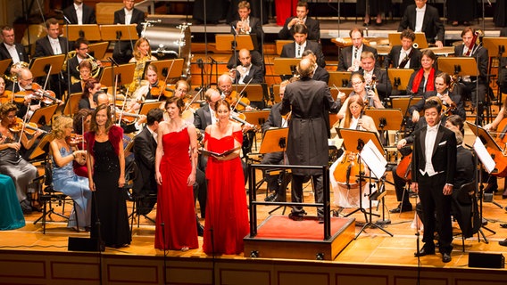 Konzertszene der Opening Night: Vor Thomas Hengelbrock und dem NDR Elbphilharmonie Orchester stehen die Gesangssolisten Katharina Sabrowski, Alexandra Hebart, Judith van Wanroij und Keunhyung Lee (v.l.). © NDR Foto: Axel Herzig