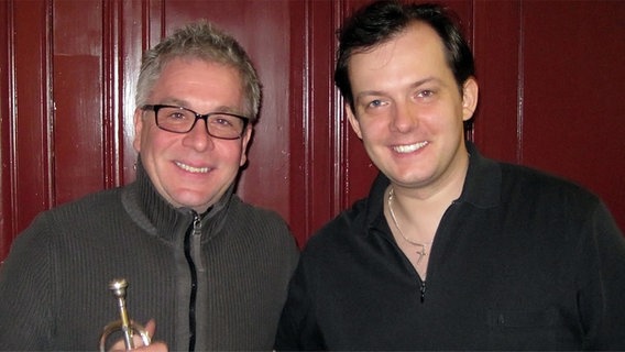 Trompeter Håkan Hardenberger und Dirigent Andris Nelsons im Porträt vor rotem Hintergrund © NDR Sinfonieorchester 