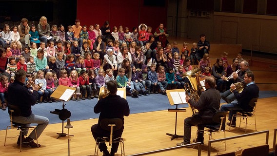 Fünf Blechbläser spielen vor einer großen Gruppe Kindergartenkinder, die ihnen gegenüber sitzen. © NDR Sinfonieorchester 