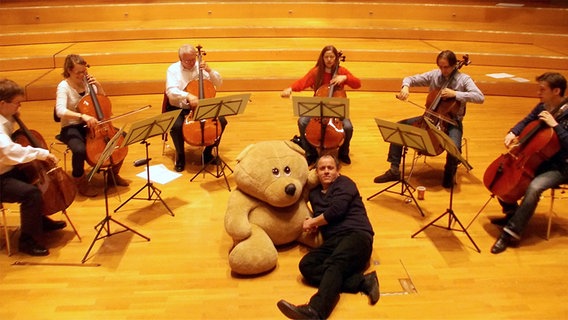 Probenszene im Rolf-Liebermann-Studio: Die Cellisten des NDR Sinfonieorchesters, Erzähler Jens Peter Brose und Teddybär Washable. © NDR Sinfonieorchester 