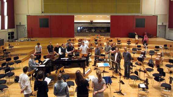 Probenszene: Thomas Hengelbrock und Musiker des NDR Sinfonieorchesters stehen rund um den Flügel im Rolf-Liebermann-Studio. © NDR Sinfonieorchester 