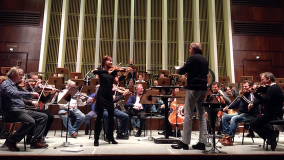 Dirigent, Violinistin und Orchester in Zivil bei einer Anspielprobe © NDR 