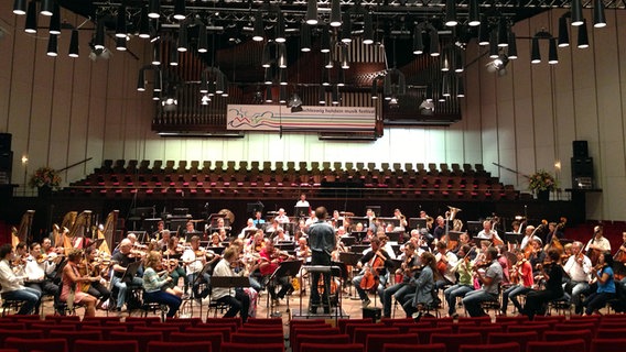 Probenszene: Blick auf die Bühne des Kieler Schlosses, auf der Marc Albrecht die Anspielprobe des NDR Sinfonieorchesters leitet. © NDR 