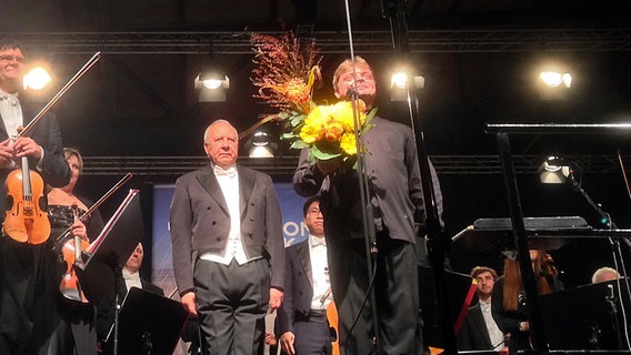 Konzertszene: Musiker, Dirigent und Solist (mit Blumenstrauß) stehen für den Schlussapplaus © NDR 