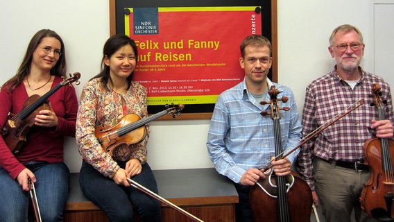 Vier Streicher des NDR Sinfonieorchester vor einem Plakat für das NDR Familienkonzert im Rolf-Liebermann-Studio © NDR 