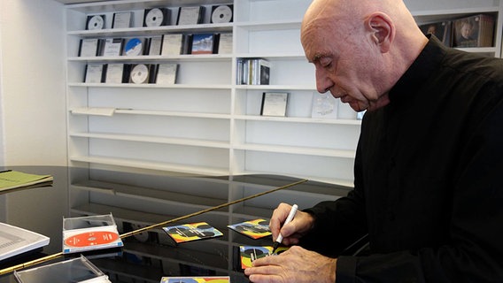 Christoph Eschenbach signiert an einem Flügel stehend CDs © NDR 
