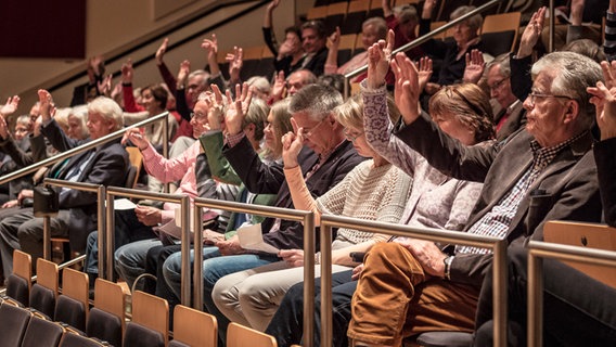 Publikum auf den Rängen hebt die Hand. © NDR 