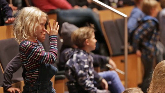 Eine Grundschülerin dreht bei einem "Konzert statt Schule" im Rolf-Liebermann-Studio eine lange Nase. © NDR Foto: Screenshot