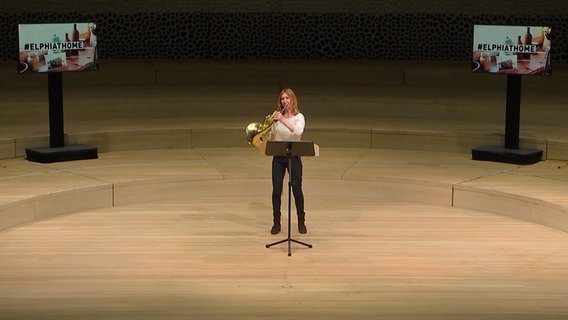 Screenshot: Hornistin Claudia Strenkert auf der leeren Bühne des Großen Saals in der Elbphilharmonie Hamburg © NDR Foto: Screenshot