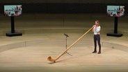 Screenshot: Hornistin Claudia Strenkert vom NDR Elbphilharmonie Orchester spielt Alphorn auf der Bühne der Elbphilharmonie Hamburg © NDR Foto: Screenshot