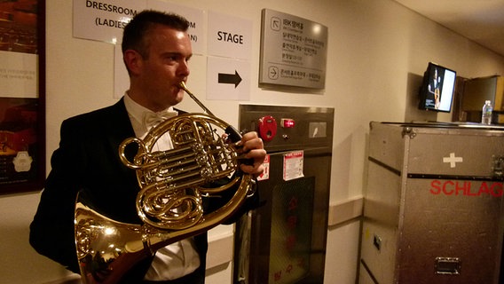 Hornist Tobias Heimann spielt sich backstage ein.  