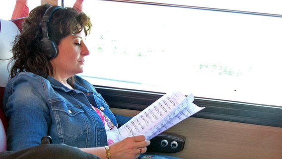 Ruxandra Klein mit Noten und Kopfhörern im Bus © NDR Sinfonieorchester 