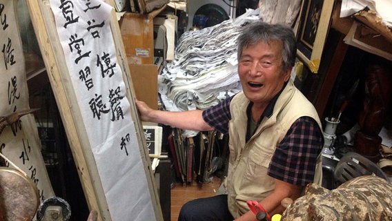Mann malt koreanische Schriftzeichen auf eine Fahne  