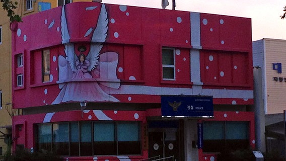 Pink angestrichene Polizeiwache mit großem Engel auf der Fassade in Daegu © NDR Sinfonieorchester 