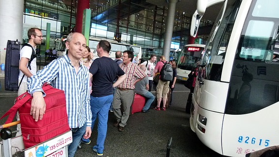 Bratscher und Orchesterarzt Thomas Oepen mit roter Arzttasche vor dem Flughafengebäude Bratscher und Orchesterarzt Thomas Oepen mit roter Arzttasche vor dem Flughafengebäude © NDR Sinfonieorchester