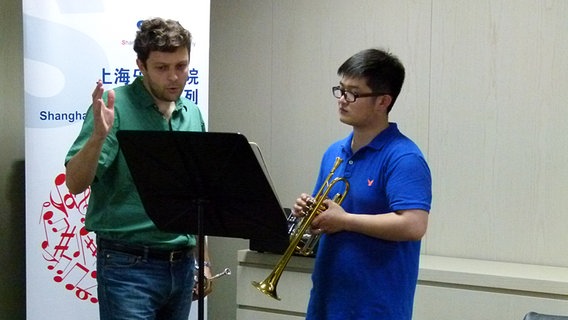 Guillaume Couloumy und Trompeter Yao Tianhao hinter einem Notenpult  