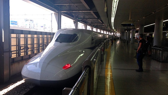 Der japanische Hochgeschwindigkeitszug Shinkansen fährt in einen Bahnhof ein  