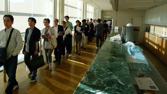 Japanische Konzertbesucher warten in einer Schlange im Foyer  