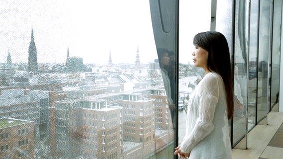 Unsuk Chin steht vor einem Fenster in der Elbphilharmonie. © NDR 