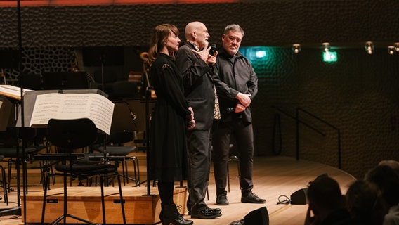 Chefdirigent Alan Gilbert spricht mit Lisa Streich und Brett Dean auf der Bühne der Elbphilharmonie beim Eröffnungskonzert von "Elbphilharmonie Visions". © NDR Foto: Daniel Dittus