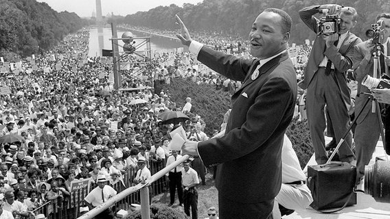 Der US-Bürgerrechtler Martin Luther King winkt bei einer Kundgebung von der Lincoln-Gedächtnisstätte in Washington aus seinen Anhängern zu. (Archivbild vom 20. August 1963) © picture-alliance/ dpa / AFP 