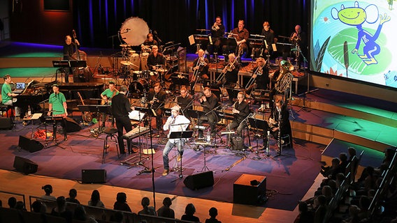 NDR Bigband beim Konzert im Rolf-Libermann-Studio, im Hintergrund eine Leinwand mit "Kuno Knallfrosch". © NDR Foto: Marcus Krüger