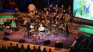 NDR Bigband beim Konzert im Rolf-Libermann-Studio, im Hintergrund eine Leinwand mit "Kuno Knallfrosch". © NDR Foto: Marcus Krüger