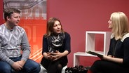 Geprächsszene: Alexander Hrustevich (links) mit Übersetzerin sitzt Moderatorin Jessica Schlage (rechts) gegenüber (Screenshot) © NDR 