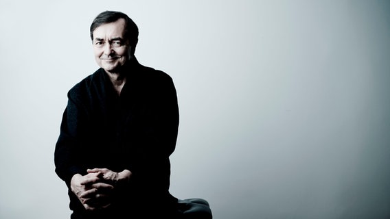 Der Pianist Pierre Laurent Aimard sitzt in schwarzer Kleidung vor einem hellgrauen Hintergrund. © NDR Foto: Marco Borggreve