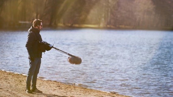 Filmdreh am Hannoverschen Maschsee für die KonzertPlus-Produktion "Solveigs Lied" der NDR Radiophilharmonie: Tonmann hält ein Mikrofon über die Wellen und fängt das Geräusch des Wassers ein © NDR Foto: Micha Neugebauer