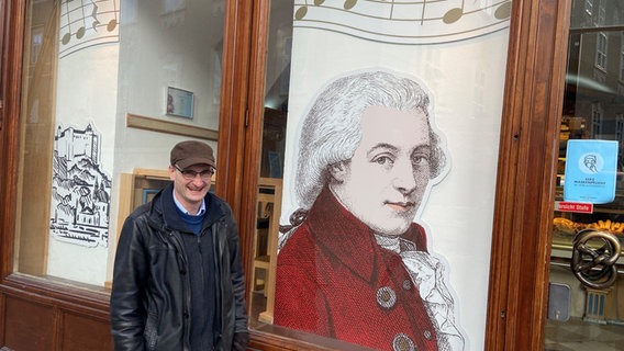 Dirigent Andrew Manze vor einer Abbildung von Mozart in einem Schaufenster © NDR Foto: Friederike Westerhaus