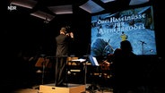 Der Film "Drei Haselnüsse für Aschenbrödel" auf großer Leinwand, davor Dirigent Frank Strobel © NDR Foto: Christian Bernstorf
