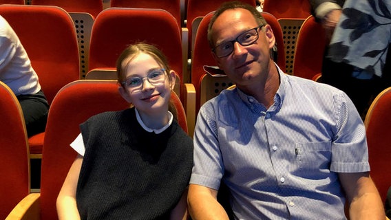 Annika Fischer, die Gewinnerin der Osterei-Aktion von Discover Music!, mit ihrem Vater beim Konzert der Orchester-Detektive am 13. Mai 2022 © NDR Foto: Bettina Pohl