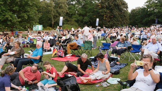 Die Zuschauer von "Hannover Proms" verfolgen die Live-Übertragung des Konzerts im Stadtpark und sitzen in Campingstühlen. © NDR Foto: Julius Matuschik