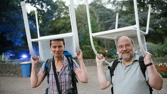 Zwei Besucher von "Hannover Proms" halten Stühle über ihren Köpfen. © NDR Foto: Julius Matuschik