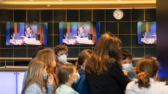 Schüler*innen im Foyer des NDR in Hannover, im Hintergrund Werbung für das Konzert der Orchester-Detektive mit Malte Arkona © NDR Foto: Helge Krückeberg